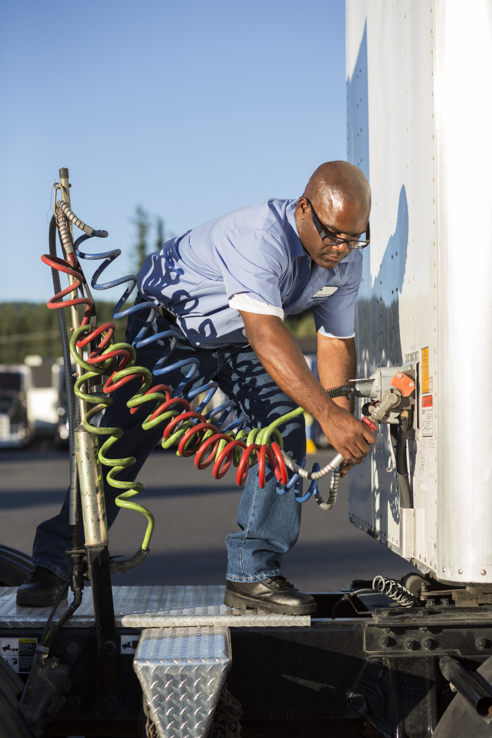 Man connecting trailer cables, backed by wrecker Houston service.